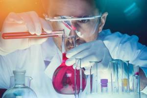 ink chemist examining lab beakers filled with fluids